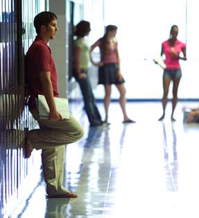 Student holding book leans on lockers