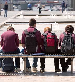 Students with backpacks sit on a bench