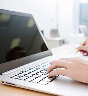 Hands typing on a laptop keyboard