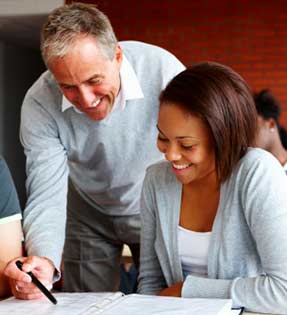 Male teacher assists female student with classwork