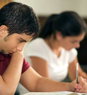 Male student writes in a notebook